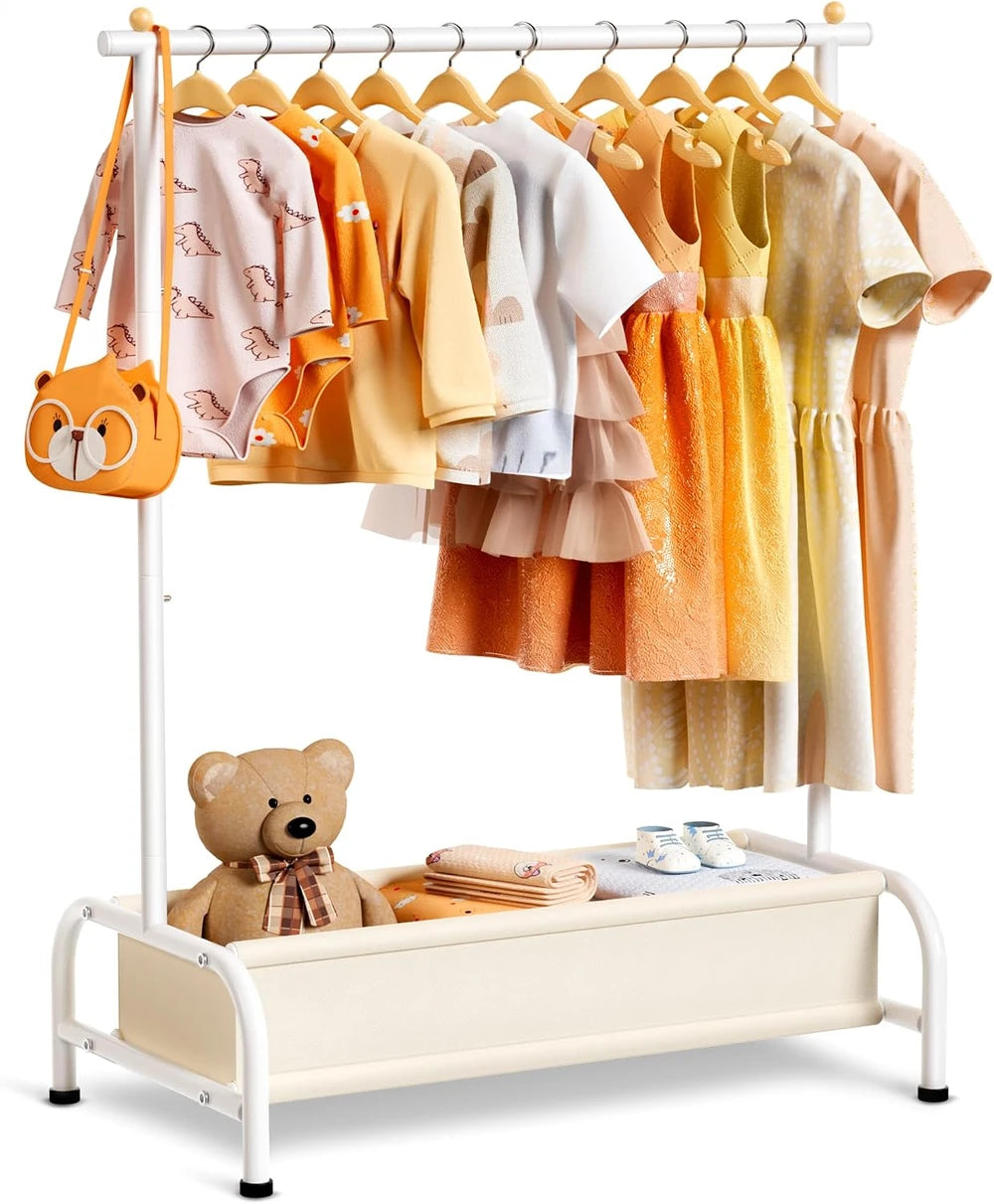 A & M BOUTIQUE white metal kids clothing rack with a bottom storage basket filled with a teddy bear and baby clothes.