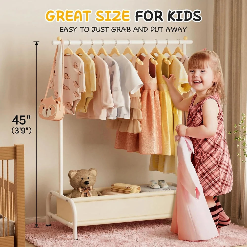 A & M BOUTIQUE white kids clothing rack with a bottom storage basket, holding children's clothes in a playroom.